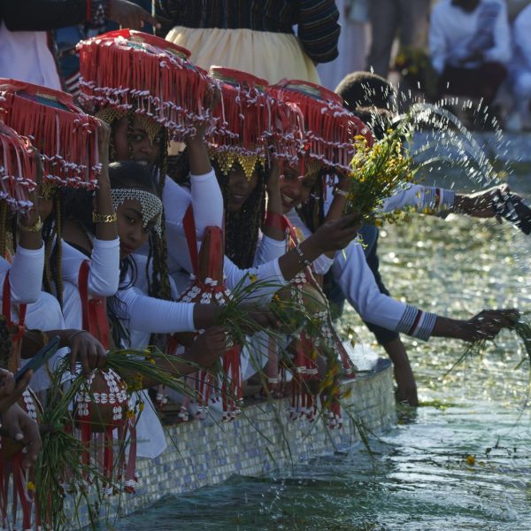 Celebrants dipping grass and flowers in water at Irreecha